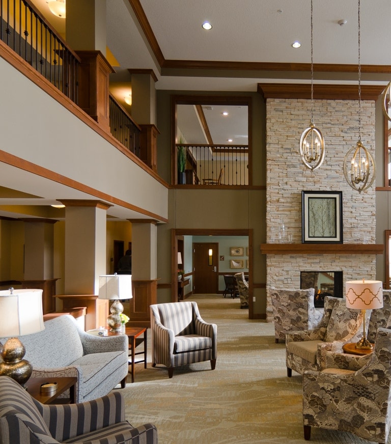 Hotel lobby with a stone fireplace, comfy chairs, and warm lighting in a spacious lounge area.